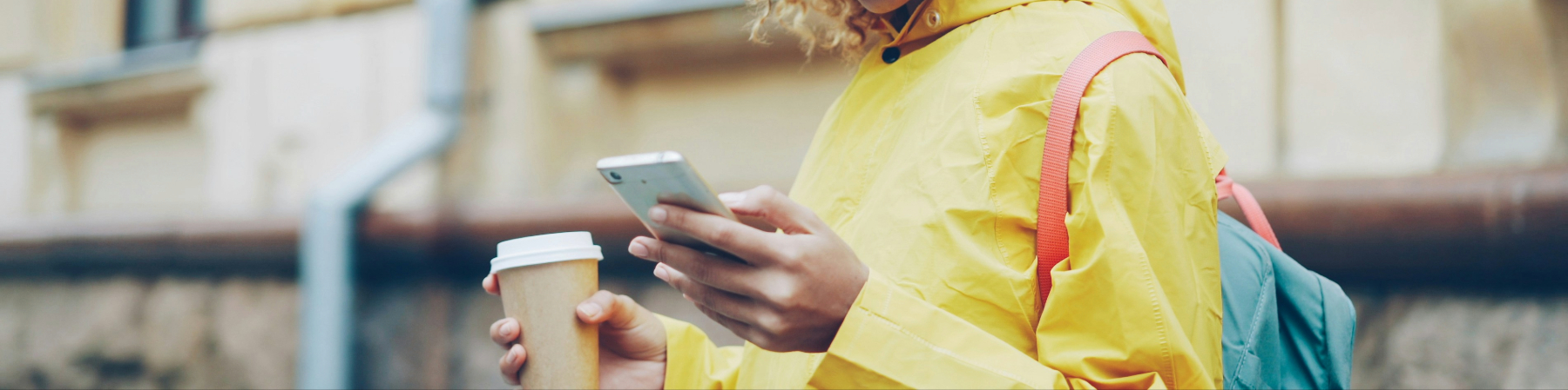 Looking at smartphone outside with a coffee