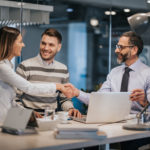 A couple shake hands with their banker while closing an apparent deal