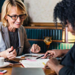 A woman signing financial papers with a businesswoman